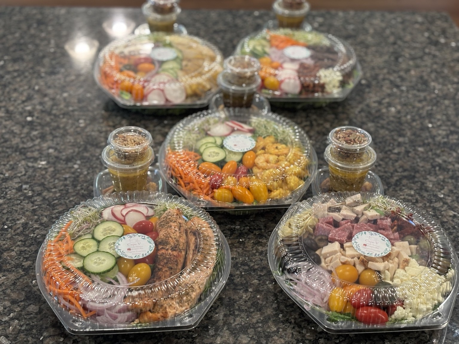 Fresh gourmet meal-prep bowls with colorful vegetables, greens and chef-made dressing