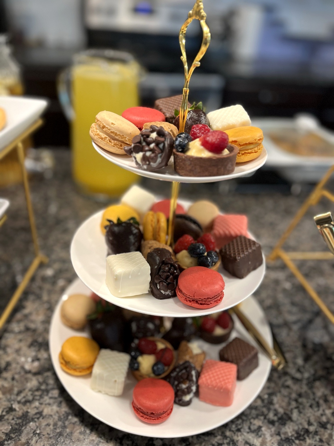 Tiered dessert tower with macarons, chocolates, petit fours and fresh berries